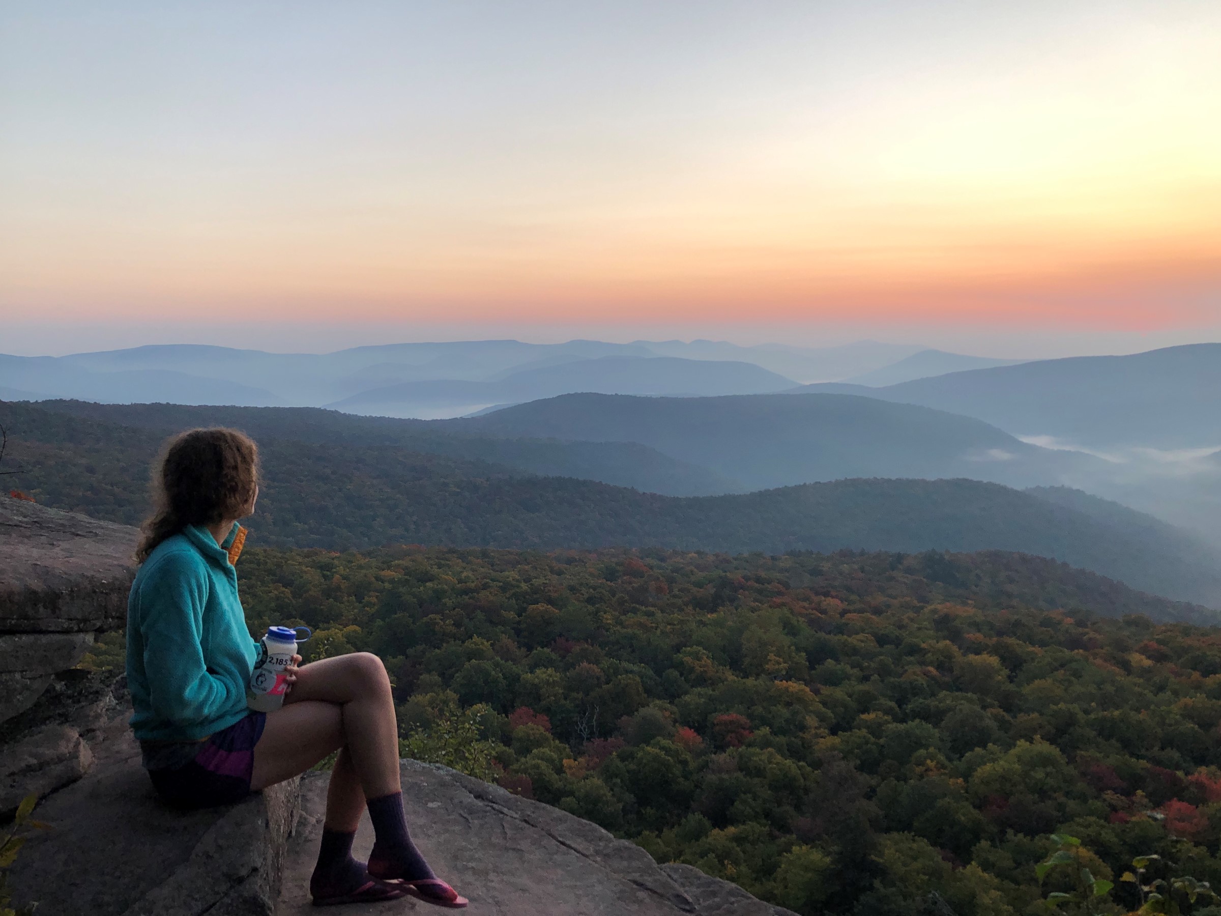 Woman on the top of a mountain looking at a sunset